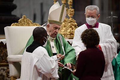El Papa Francisco le entrega un crucifijo a una mujer durante la misa en la basílica de San Pedro en la cual confirió el ministerio de catequistas y lectores a varios hombres y mujeres de diferentes continentes.