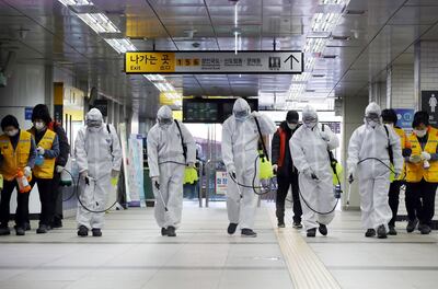 Trabajadores vestidos con trajes de protección desinfectan una estación de metro en Seúl.
