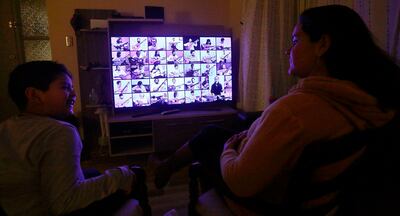 Una madre y su hijo siguen la transmisión a través de un televisor de la octava versión del homenaje para Víctor Jara.