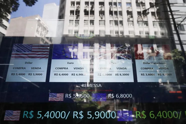 Fotografía de la ventana de una oficina de cambio con carteles que anuncian los valores de compra y venta del dólar,  en Rio de Janeiro (Brasil).