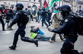 Un hombre en el suelo durante las cargas policiales en la manifestación contra la reforma del sistema de pensiones, este sábado en París, Francia.