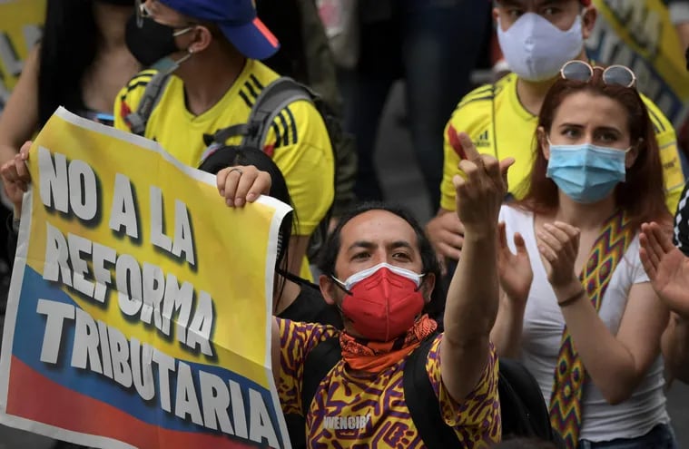 A man holds a signal that reads "No to the tax reform" during a demonstration against the tax reform proposed by the Colombian President Ivan Duque, in Bogota, on April 28, 2021. - Workers' unions, teachers, civil organizations, indigenous people and other sectors reject the project that is underway in Congress, considering that it punishes the middle class and is inappropriate in the midst of the crisis unleashed by the pandemic. (Photo by Raul ARBOLEDA / AFP)