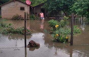 Mujer camina en el agua. La lluvia inundó su casa e inutilizó varias de sus pertenencias.
