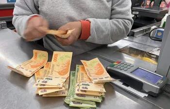 El cajero de un comercio cuenta los billetes de pesos argentinos en un centro comercial.