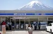 Una turista extranjera posa frente a una tienda de convencia Lawson con el Monte Fuji detrás en Fujikawaguchiko.