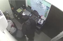 Momento en que el cajero de Sunset Cubiertas es obligado a cargar el dinero por uno de los delincuentes. El trabajador acusó tres impactos de bala.