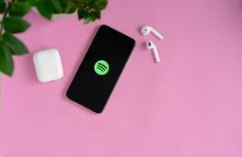 Un teléfono celular conectado a Spotify con dos auriculares