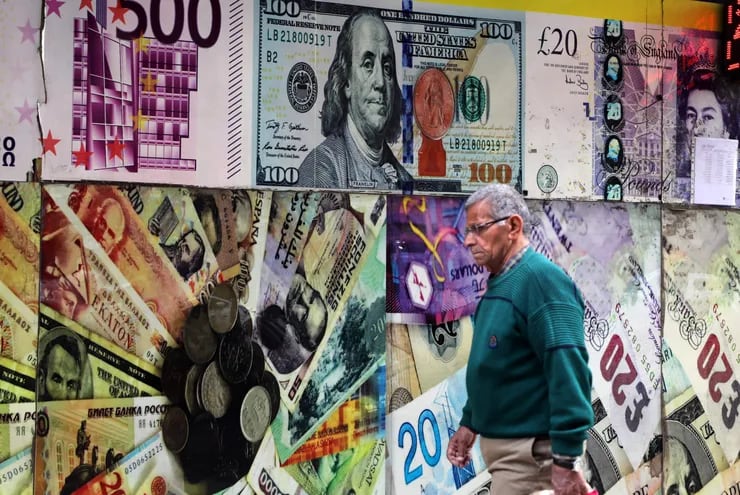 Un hombre pasa junto a una imagen a gran escala de un billete de dólar estadounidense en una oficina de cambio de divisas en El Cairo, Egipto.