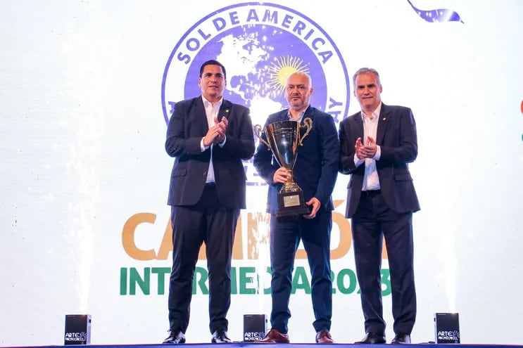 El presidente del club Sol de América, Óscar Giagni (centro) posa con el trofeo de campeón de la División Intermedia.