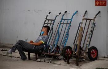 Un trabajador migrante se echa una siesta mientras espera para conseguir un empleo, en Pekín.