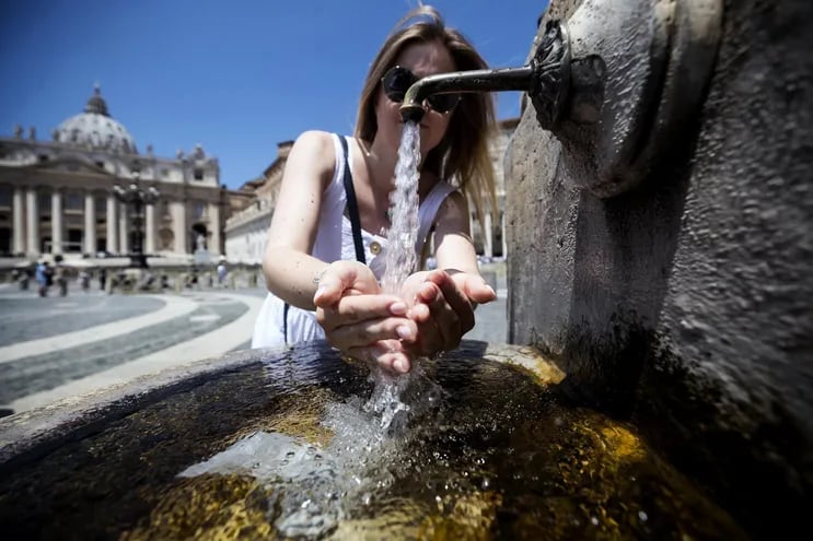 Una viandante se refresca en una fuente del centro de Roma (Italia).