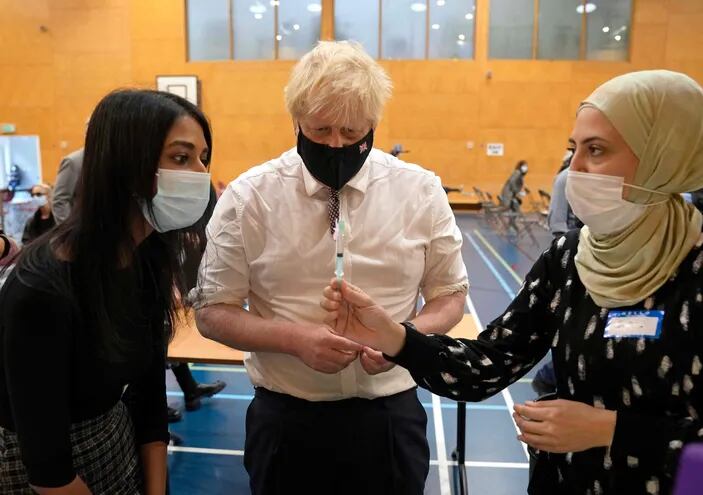 El primer ministro británico Boris Johnson observa cuando una sanitaria prepara una dosis de la vacuna contra el Covid-19.