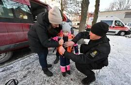 Voluntarios le prueban un chaleco antibalas a una niña en Kharkiv, Ucrania.