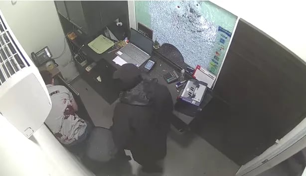 Momento en que el cajero de Sunset Cubiertas es obligado a cargar el dinero por uno de los delincuentes. El trabajador acusó tres impactos de bala.