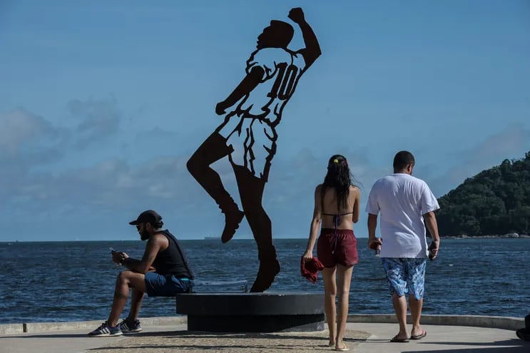 Se ve a personas junto a una estatua que representa a la leyenda del fútbol brasileño Pelé, diseñada por el artista brasileño Luis Costa, en el muelle Rei Pele, en Sao Vicente, costa del estado de Sao Paulo, Brasil.