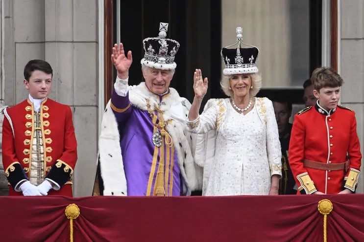El rey Carlos III de Gran Bretaña con la corona del estado imperial y la reina Camila de Gran Bretaña con una versión modificada de la corona de la reina María saludan desde el balcón del Palacio de Buckingham después de ver el vuelo de la Royal Air Force en el centro de Londres el 6 de mayo de 2023, después de sus coronaciones.