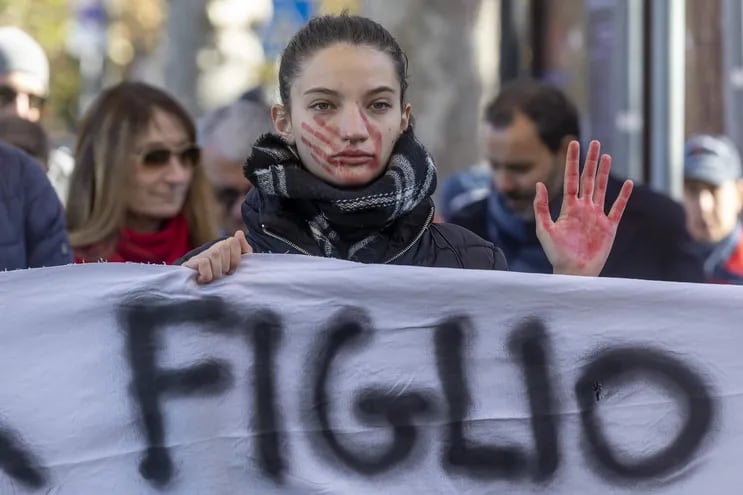 Una activista levanta una mano manchada de sangre y muestra un hematoma en forma de mano en su rostro durante una protesta con motivo del día Internacional para la Eliminación de Violencia contra las mujeres, en Italia.