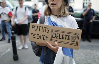 Una mujer de la diáspora rusa sostiene un cartel con la leyenda "Regimen de Putin. ELIMINAR".