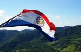 La bandera paraguaya flameando desde la cima del Cerro Acatí con un imponente paisaje de las serranías del Ybytyruzú.