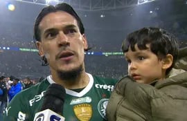 Gustavo Gómez, con su hijo en brazos, dando una entrevista dentro del campo de juego.