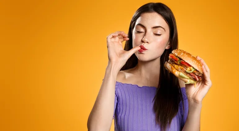 Mujer comiendo hamburguesa.