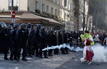 Un manifestante grita consignas mientras que la policía arroja gas lacrimógeno en París.