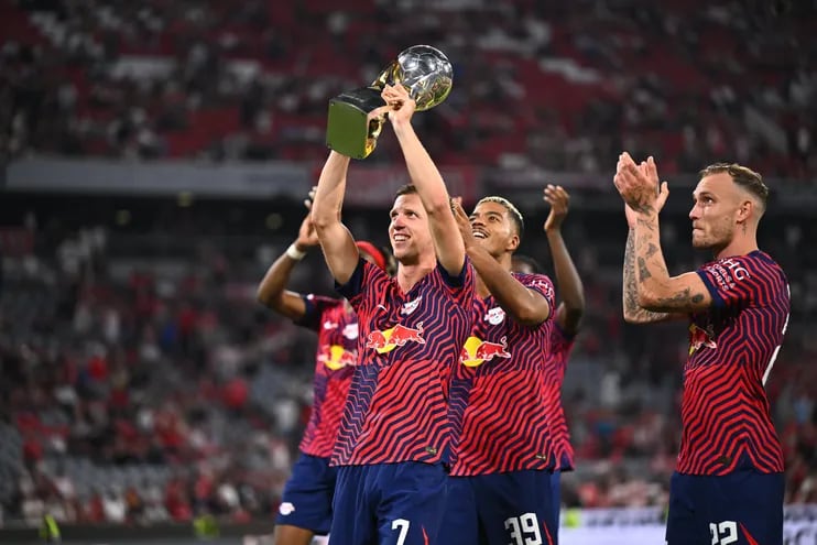 Dani Olmo levanta y exhibe al público el trofeo de la Supercopa de Alemania que el Leipzig ganó superando al Bayern Munich.