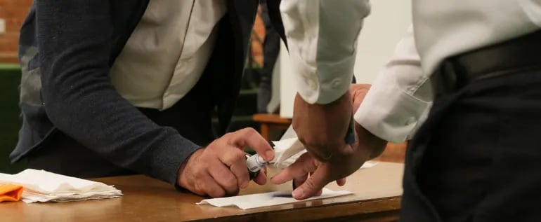 Un funcionario del Tribunal Electoral rocía con tinta el dedo de un participante del simulacro de votación realizado este lunes.