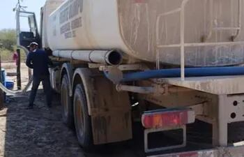 Un poblador de la localidad de San Carlos, distante a 100 kilómetros del casco urbano de Fuerte Olimpo, procede a bajar el agua tratada, llevada por el camión cisterna.