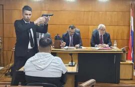 Un funcionario judicial exhibe el arma que según el testigo fue utilizada para asesinar a Robert. Al fondo, los magistrados Federico Ortiz y Héctor Fabián Escobar.