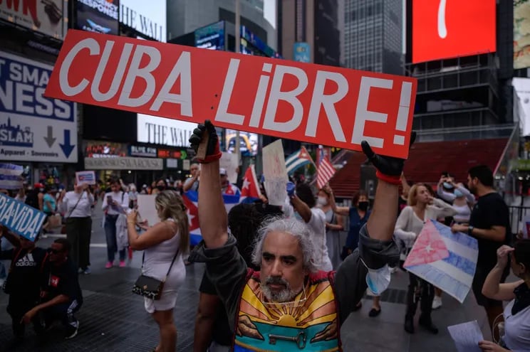 Demonstrators hold placards during a rally held in solidarity with anti-government protests in Cuba, in Times Square, New York on July 13, 2021. - One person died and more than 100 others, including independent journalists and dissidents, have been arrested after unprecedented anti-government protests in Cuba, with some remaining in custody on Tuesday, observers and activists said. (Photo by Ed JONES / AFP)