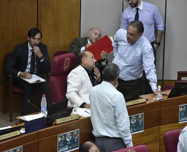 Los senadores Óscar "Cachito" Salomón (ANR, FR) (saco blanco) y el senador Hugo Richer (FG) (izq.) conversan en la sala de sesiones del Senado.
