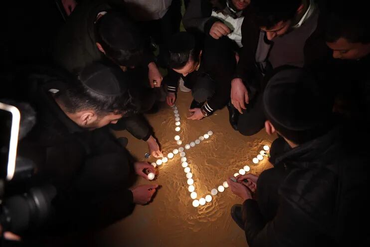 Judíos ultraortodoxos encienden velas en el lugar del tiroteo en una sinagoga en la zona de Neve Yaakov de Jerusalén, Israel. (EFE/ATEF SAFADI).
