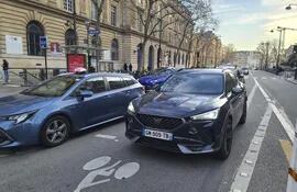 Varios coches circulan por una calle de París.