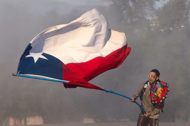 Un manifestante ondea una bandera chilena durante las protestas contra el gobierno de Sebastián Piñera.