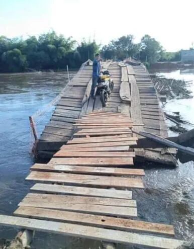 Un poblador se dispone a cruzar el rio Tebicuary sobre un precario puente de madera.