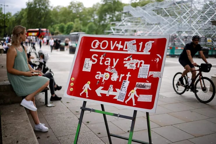Una persona descansa próxima a un cartel que indica guardar distancia para evitar la propagación del Covid-19, en el centro de Londres.
