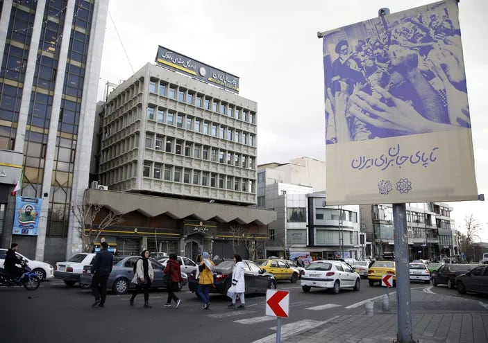 Iraníes cruzan una calle de Teherán frente a un cartel del ayatolá Ruhollah Khomeini, fundador de la revolución iraní en 1979.