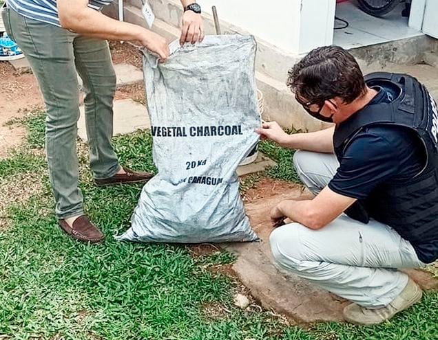 Un oficial de SIU revisa una de las bolsas de carbón que fueron halladas ayer en la casa quinta de Cristian Turrini, en San Bernardino, y que es igual a las bolsas cargadas con cocaína que fueron  halladas en el puerto Terport de Villeta.