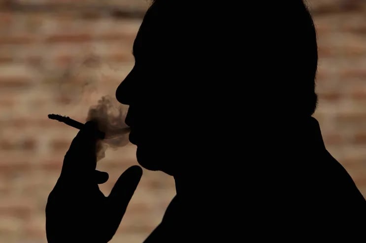La silueta de un hombre fumando.