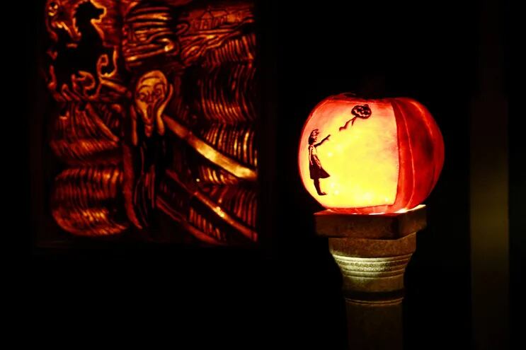 Una calabaza iluminada con la figura de "La niña con globo", del artista Bansky, y de fondo una obra inspirada en "El grito", de Munsk, forman parte de la decoración de una casa neoyorkina por Halloween.