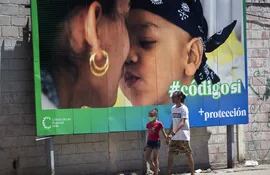 Un hombre y su hija pasan caminando frente a una valla que hace parte de la campaña por el Sí en el referendo sobre el código de familia, en La Habana.