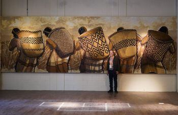 Koki Ruiz junto al mural "La recolección de los frutos" que realizó para la Exposición Universal de Dubái, utilizando semillas y arena.